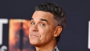 Robbie Williams smiling on the red carpet.