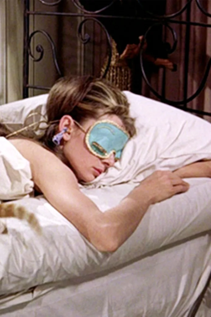 Sleepmaxxing: woman sleeping in bed with a green silk eyemask