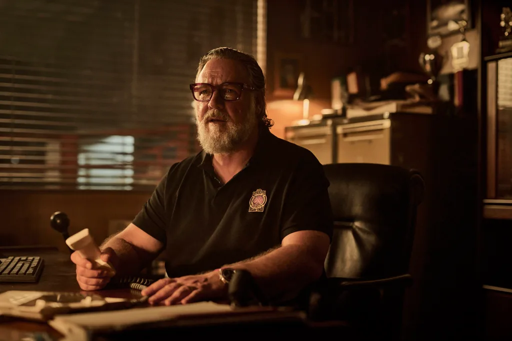 russell crowe in character as sammy in beast, sitting in a dimly lit office