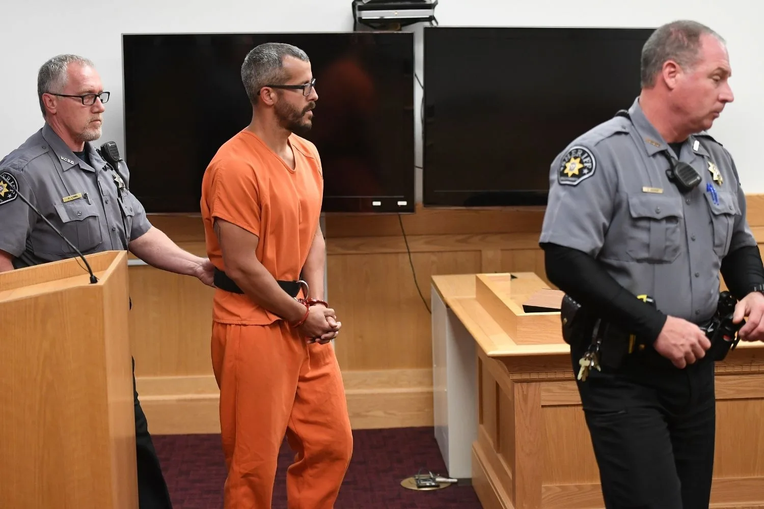 chris watts in his prison orange jumpsuit being walked into court