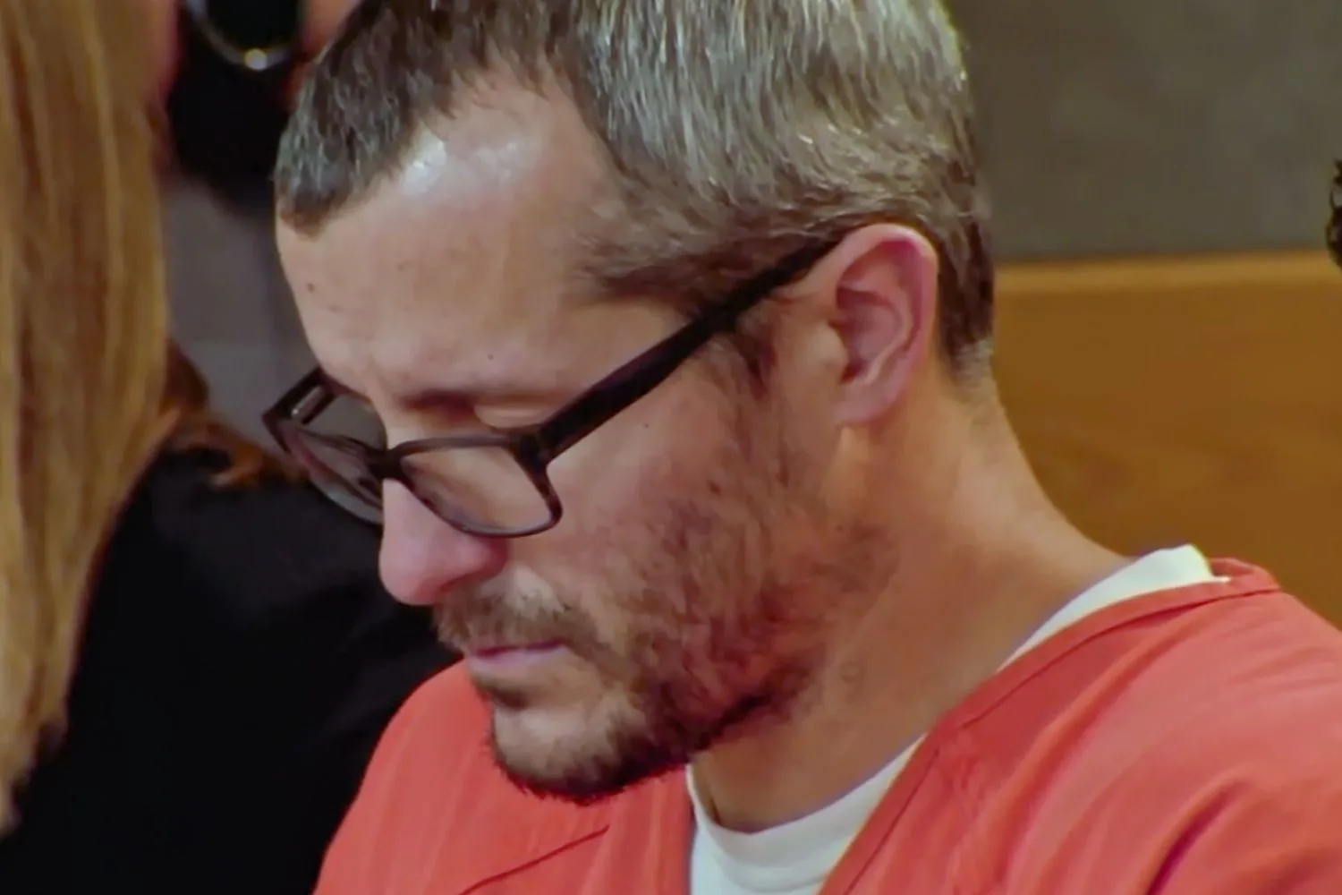 chris watts in prison jumpsuit while in court looking down and solemn
