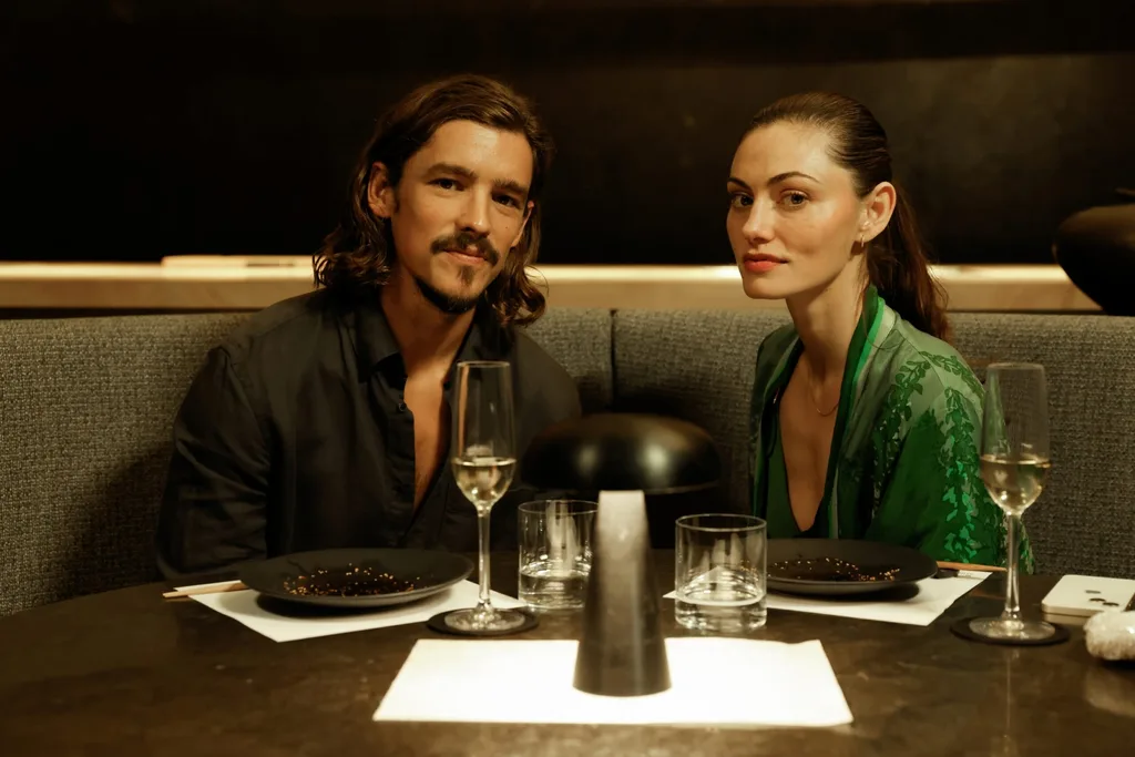 two people sit at a booth for a date looking at the camera