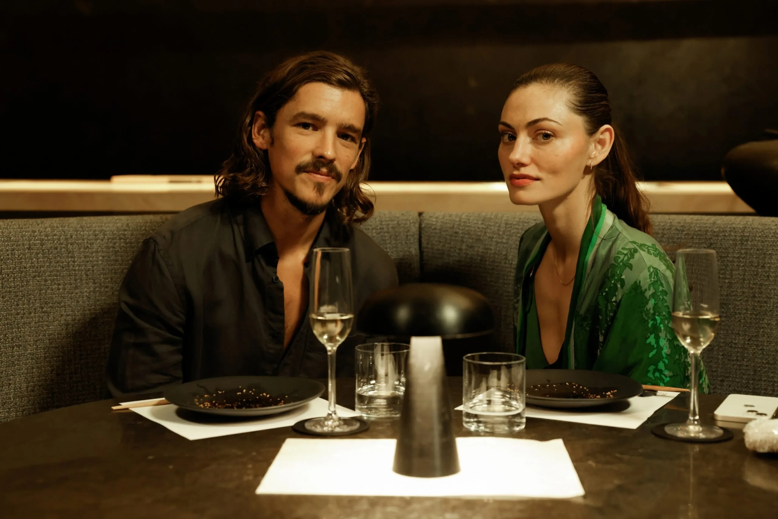 two people sit at a booth for a date looking at the camera
