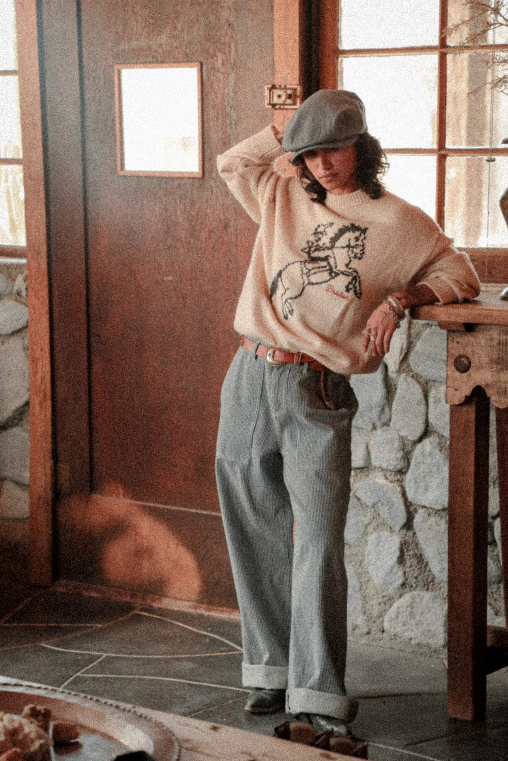 A model poses in a sweater, cap and jeans. 