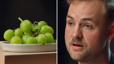 A white man looks on in horor on the right hand side as bowl of grapes taunts him on the left.
