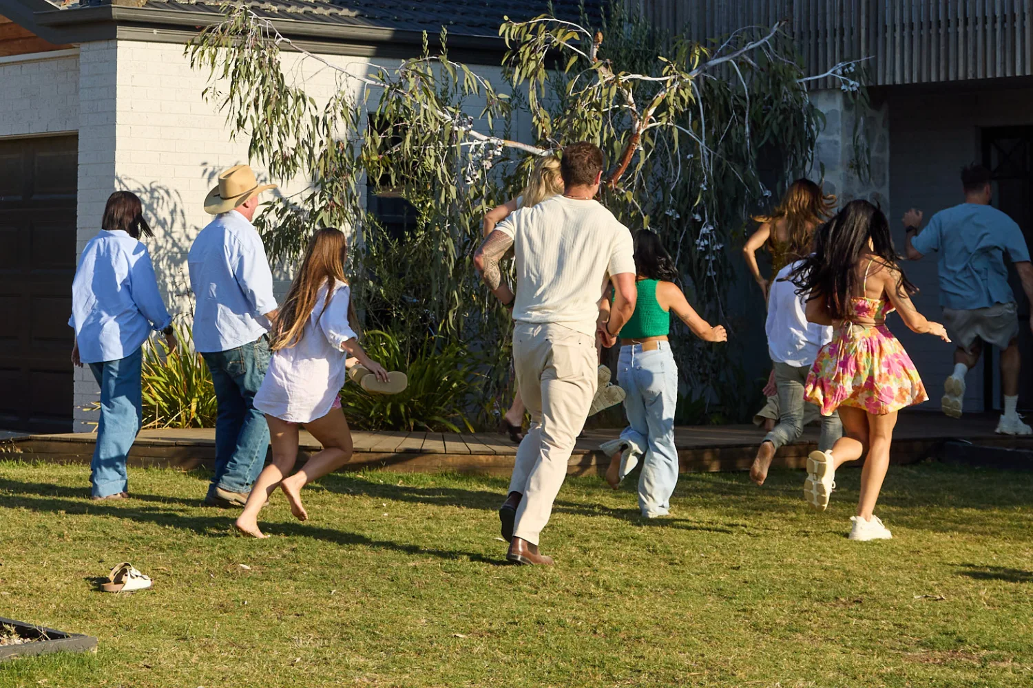 The Block contestants running into their house.