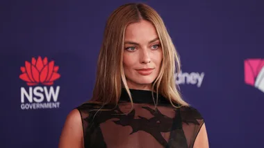 Margot Robbie on the red carpet wearing a black dress.