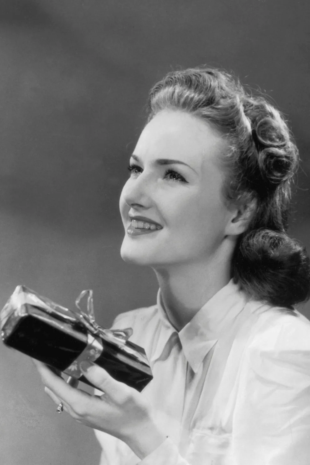 Circa 1945, A woman is delighted to receive a gift from a male admirer. 