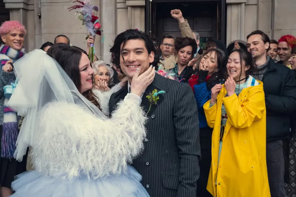 A newlywed couple celebrate outside their wedding venue, surrounded by cheering friends and family.