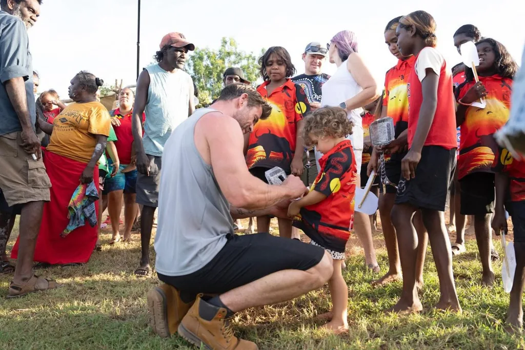 Chris Hemsworth signs his autograph on a kid's t-shirt