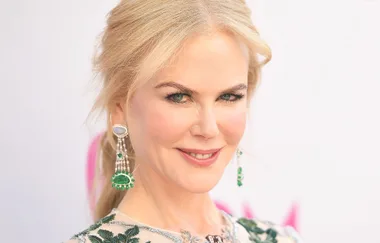Blonde woman smiling with green gemstone earrings and floral dress.