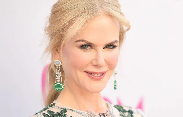 Blonde woman smiling with green gemstone earrings and floral dress.