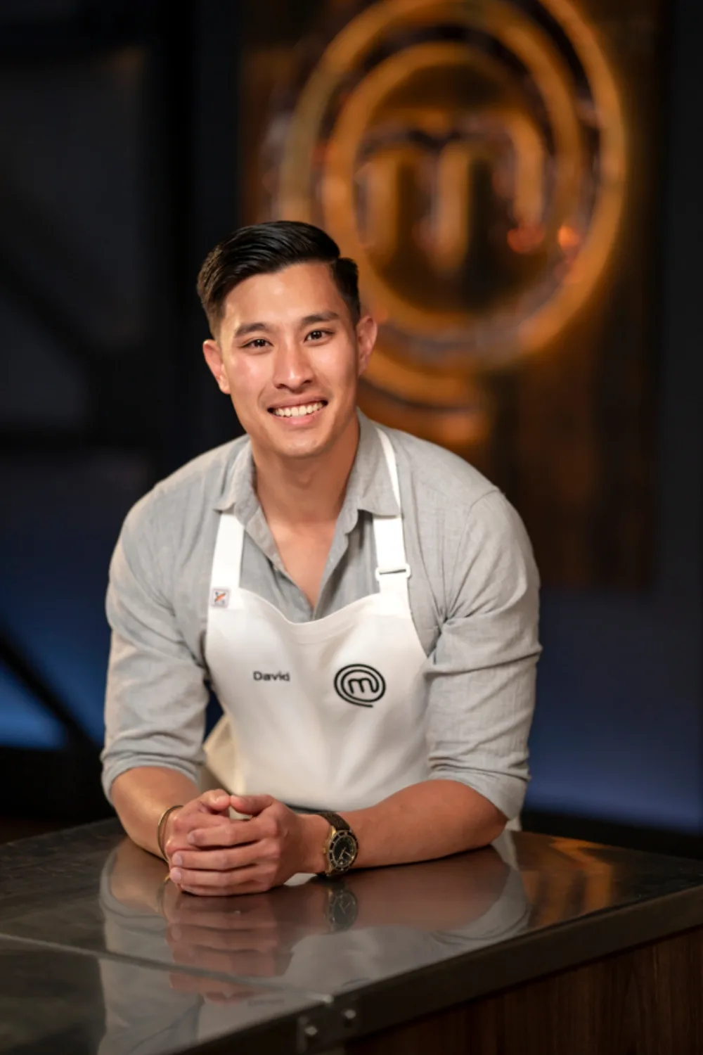 MasterChef contestant David Tan leans against countertop. 