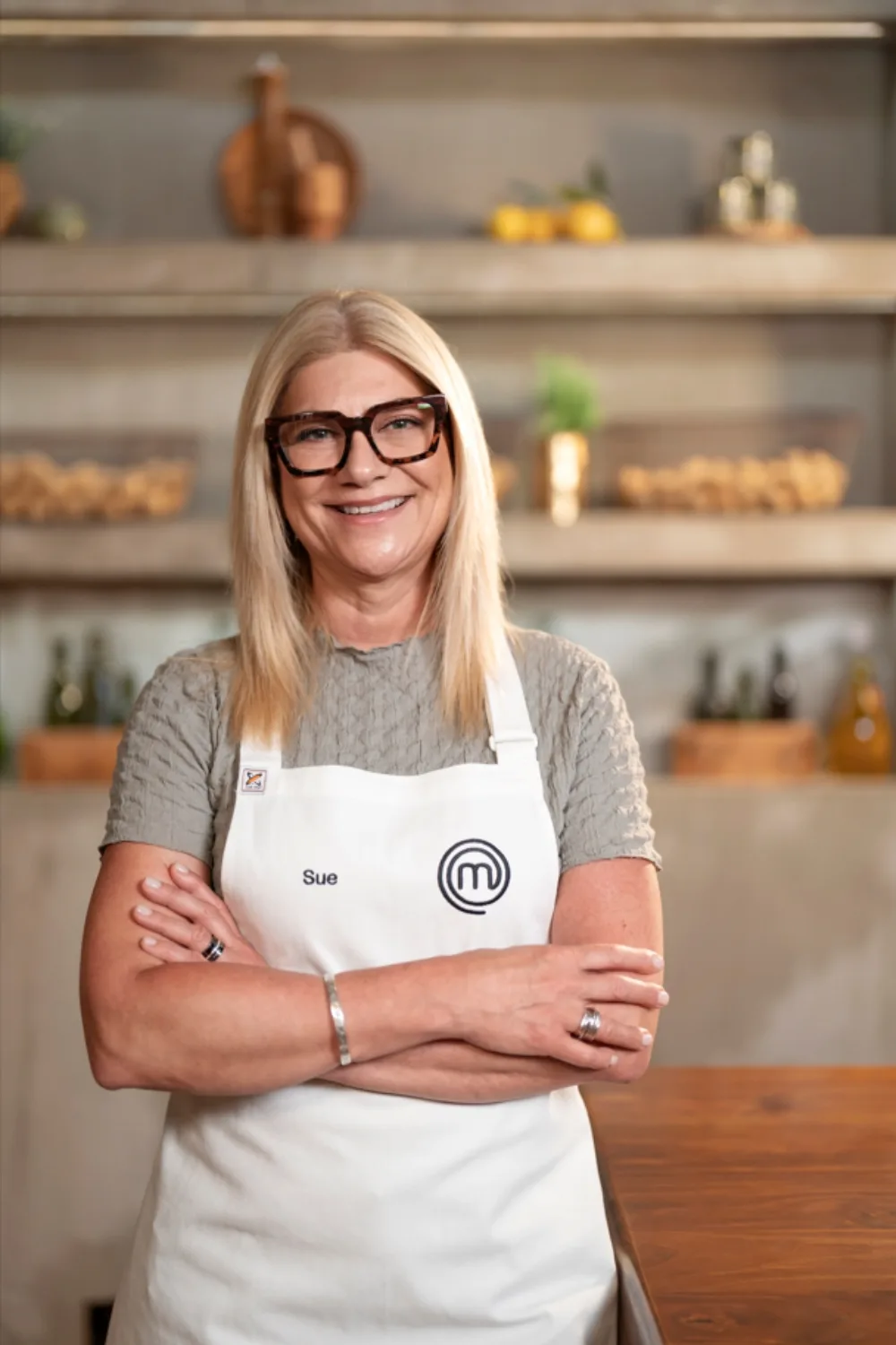 MasterChef contestant Sue standing wearing white MasterChef apron. 