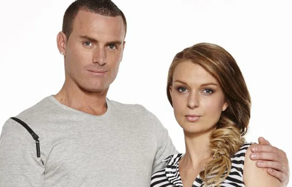 Two people posing side by side; one in a gray shirt, the other with a striped top and braided hair.