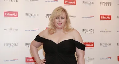 A woman in a black dress at a FilmAid event backdrop with Belvedere Vodka and Hong Kong Tatler logos.