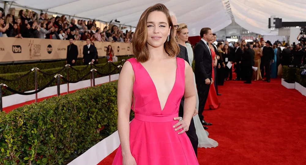 Person in a pink gown on a red carpet event, with crowds in the background.