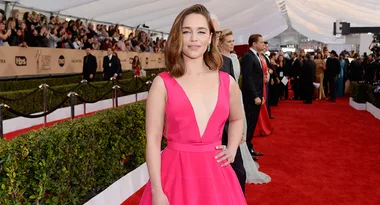 Person in a pink gown on a red carpet event, with crowds in the background.