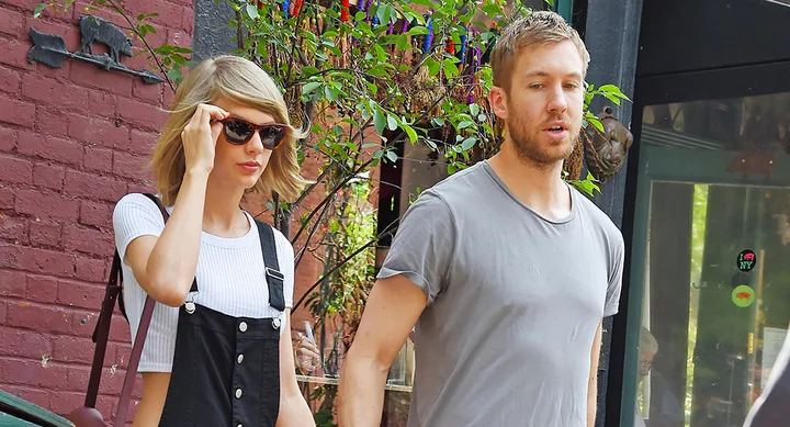 Two people walking outside, one wearing sunglasses and a black overall dress, the other in a gray t-shirt.