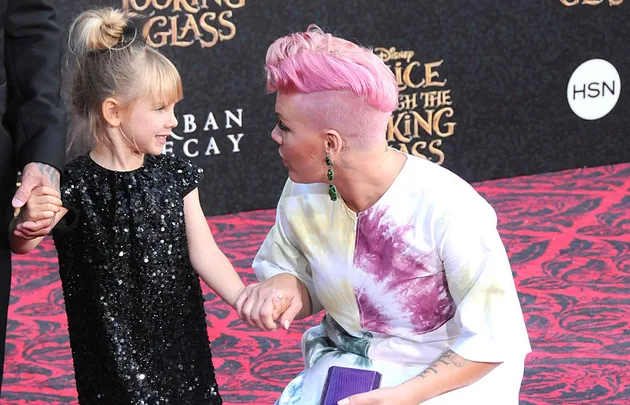 Two individuals holding hands at the "Alice Through the Looking Glass" premiere on the red carpet.