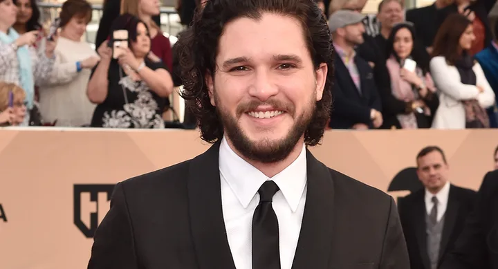 A man in a suit smiling at an event, with a crowd in the background.