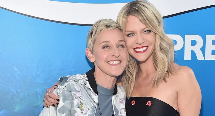 Two people smiling and posing together at an event with a blue background.
