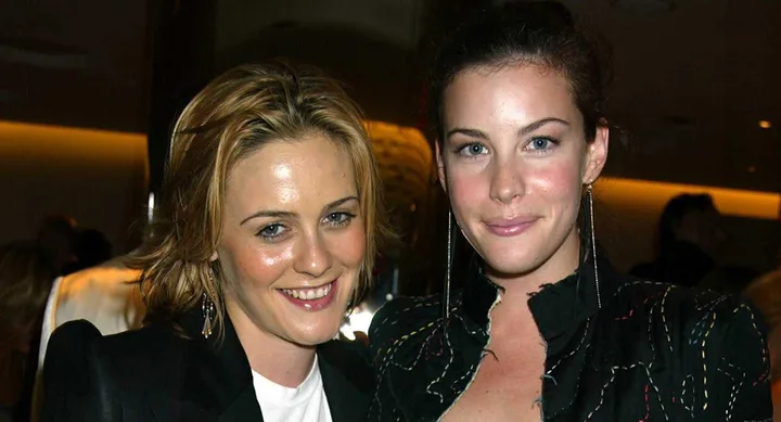 Two women smiling at a social event, with soft lighting in the background.