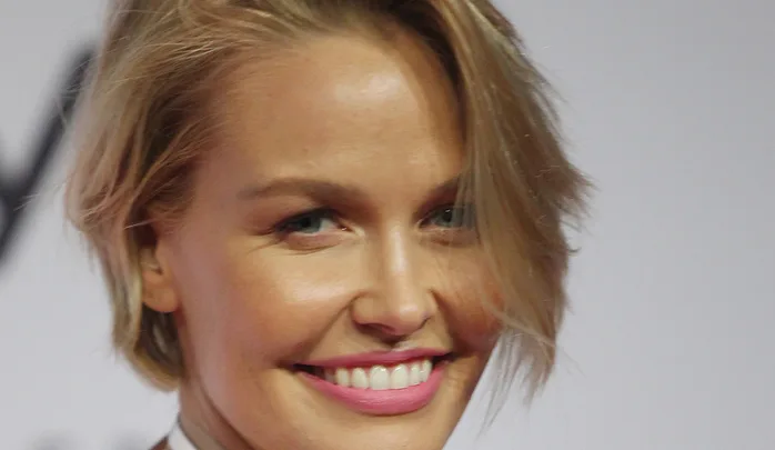 A person with short blonde hair smiling at an event.