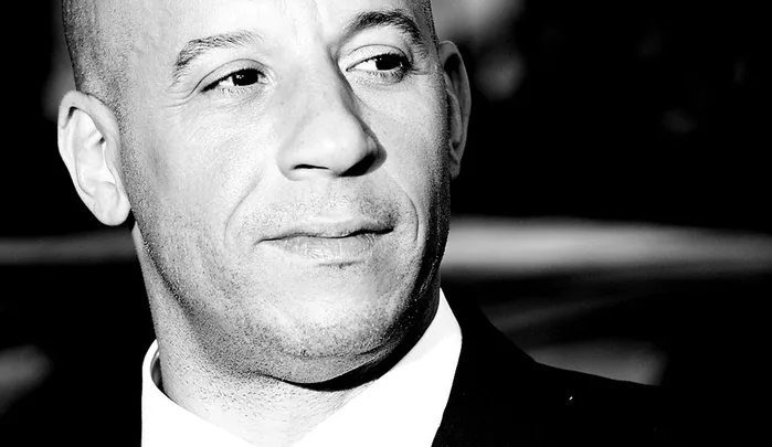 Black and white close-up of a person in a suit looking to the side.