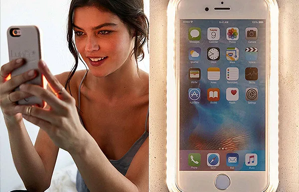 Young woman taking a selfie with a smartphone; phone screen displays various app icons.