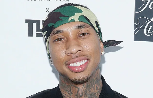 A man with tattoos wearing a camouflage headband smiles at an event backdrop.