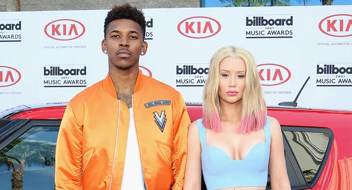 Two people posing at the 2015 Billboard Music Awards; one in an orange jacket, the other in a light blue top.