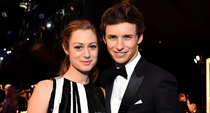 A couple posing together at a formal event, with the man in a tuxedo and the woman in a black and white dress.