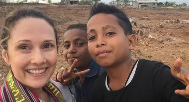 Smiling woman taking a selfie with two boys on a dry, rocky landscape.
