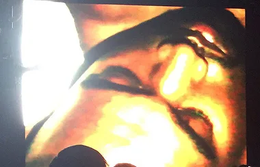 Close-up of an abstract, digitally altered face on a screen, with strong yellow and orange highlights.