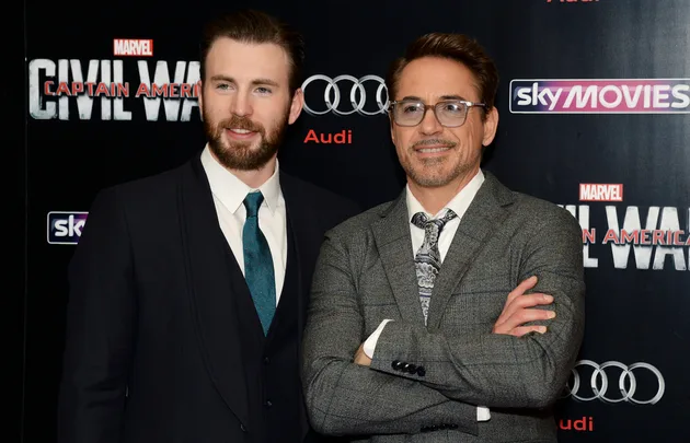 Two actors pose at the "Captain America: Civil War" premiere, standing against a backdrop with the movie title and logos.