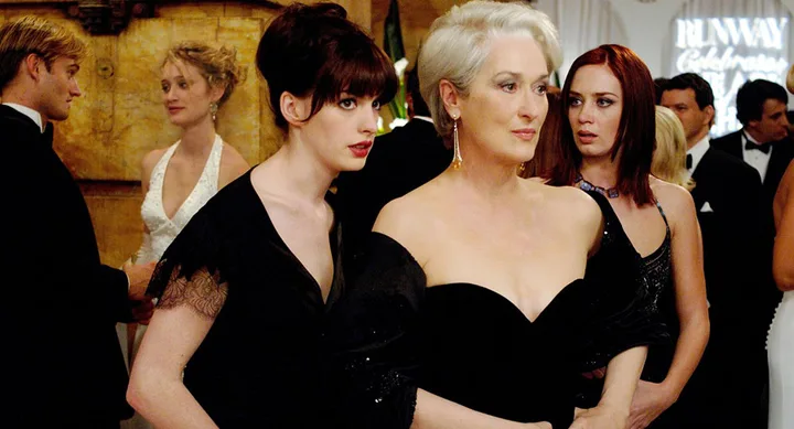 Elegant women in black dresses at a formal event, with guests mingling in the background.