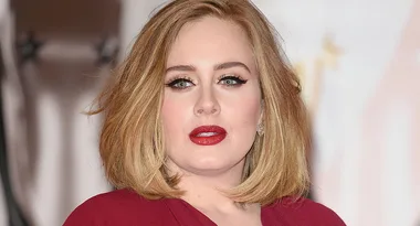 ```plaintext
Person with short blonde hair, wearing a red outfit, looking at the camera.
```