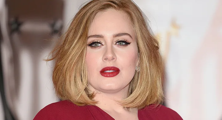 ```plaintext
Person with short blonde hair, wearing a red outfit, looking at the camera.
```