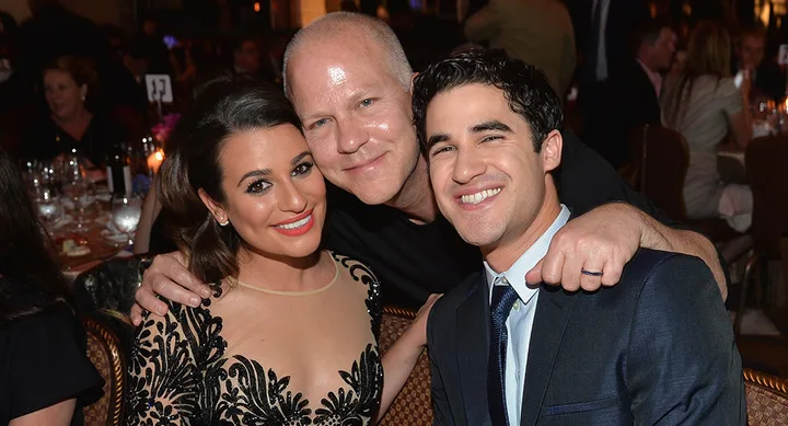 Three people smiling and posing together at a formal event, dressed in evening wear.