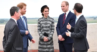 Five people in formal attire standing outdoors, engaged in conversation.