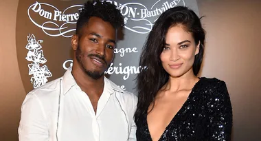 A man and a woman posing together at a formal event, with a decorative background.