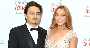 Two people posing at the Caudwell Children charity event, dressed formally, standing in front of a branded backdrop.