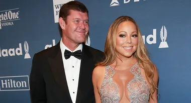 Two people in formal attire on a blue carpet; woman in sequined dress, man in black tuxedo.
