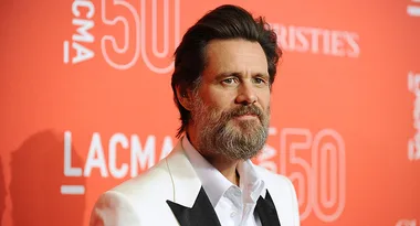 Man with a beard in a white suit at a red carpet event with "LACMA 50" backdrop.
