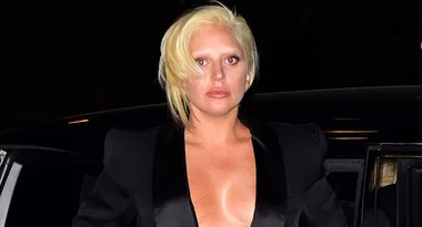 Blonde person in a black outfit exiting a car at night.