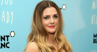 A woman with long blonde hair and a black top poses against a blue background with Montblanc branding.