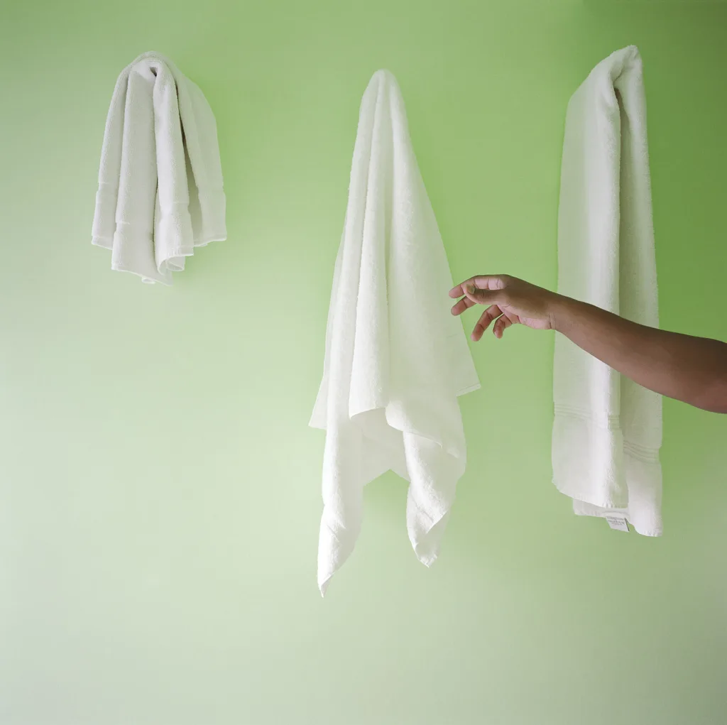 Person reaching for a towel on a green wall