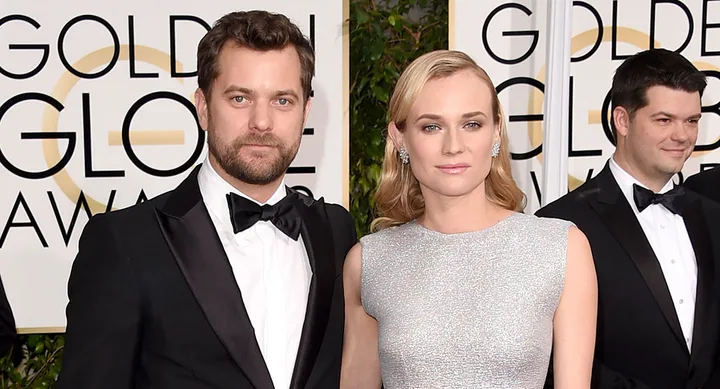 Three individuals dressed in formal attire pose at the Golden Globe Awards with the event logo in the background.