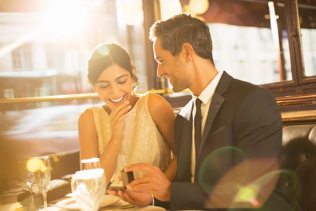 A man proposes to his girlfriend in a sun-lit restaurant